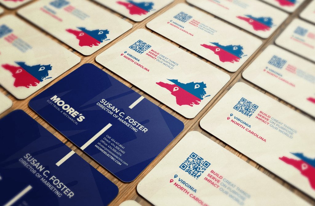 Table with multiple marketing business cards with contact details and a QR code.